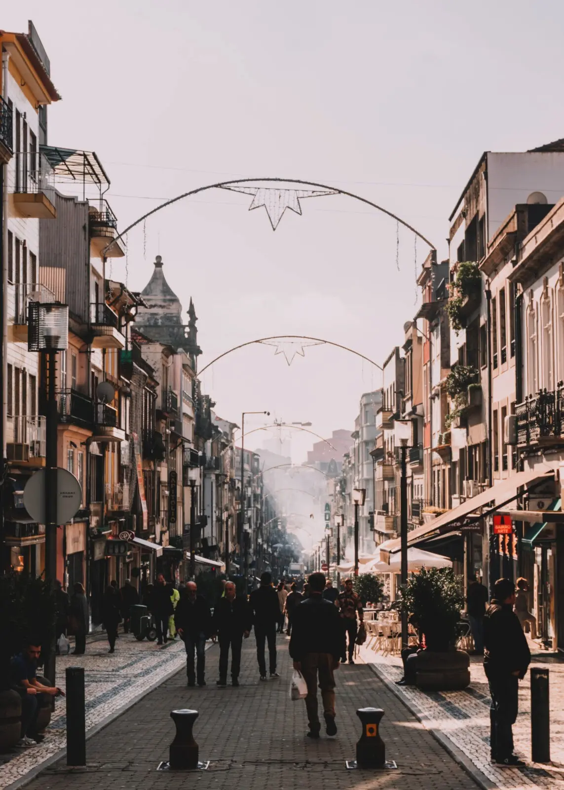 Corso in centro a Porto, pieno di gente, negozi e luminarie natalizie