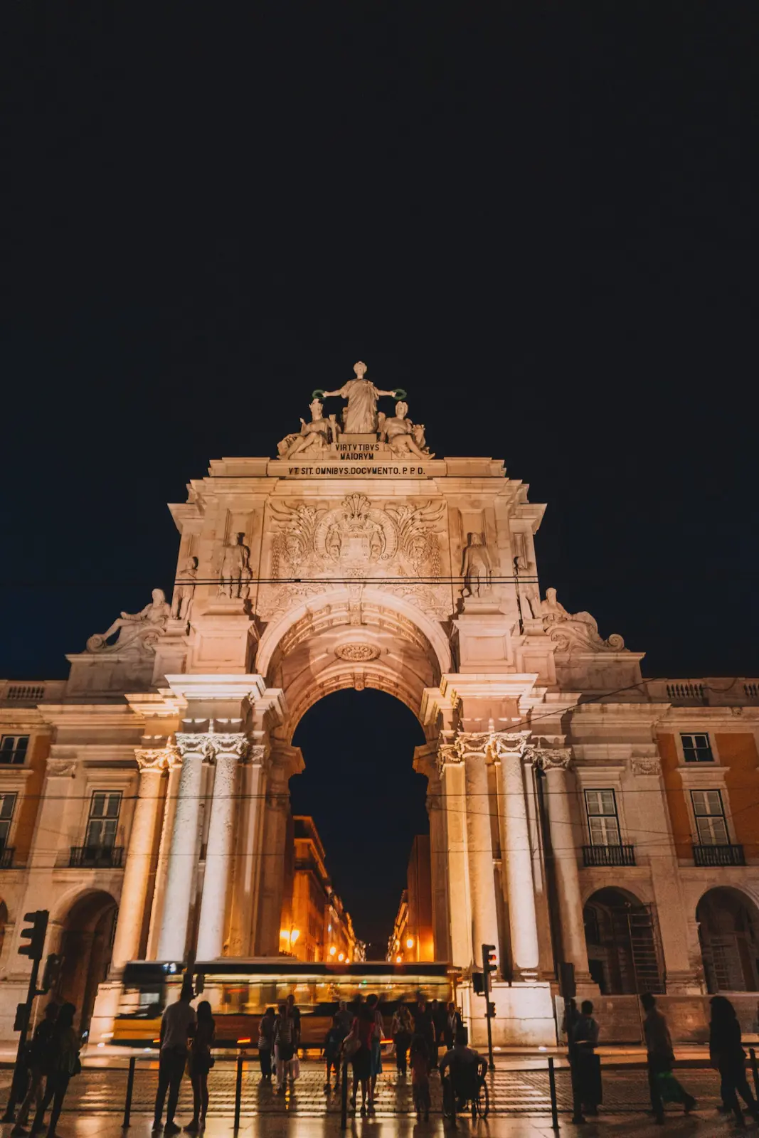 Arco della Rua Augusta di notte, con un tram giallo che sfreccia davanti