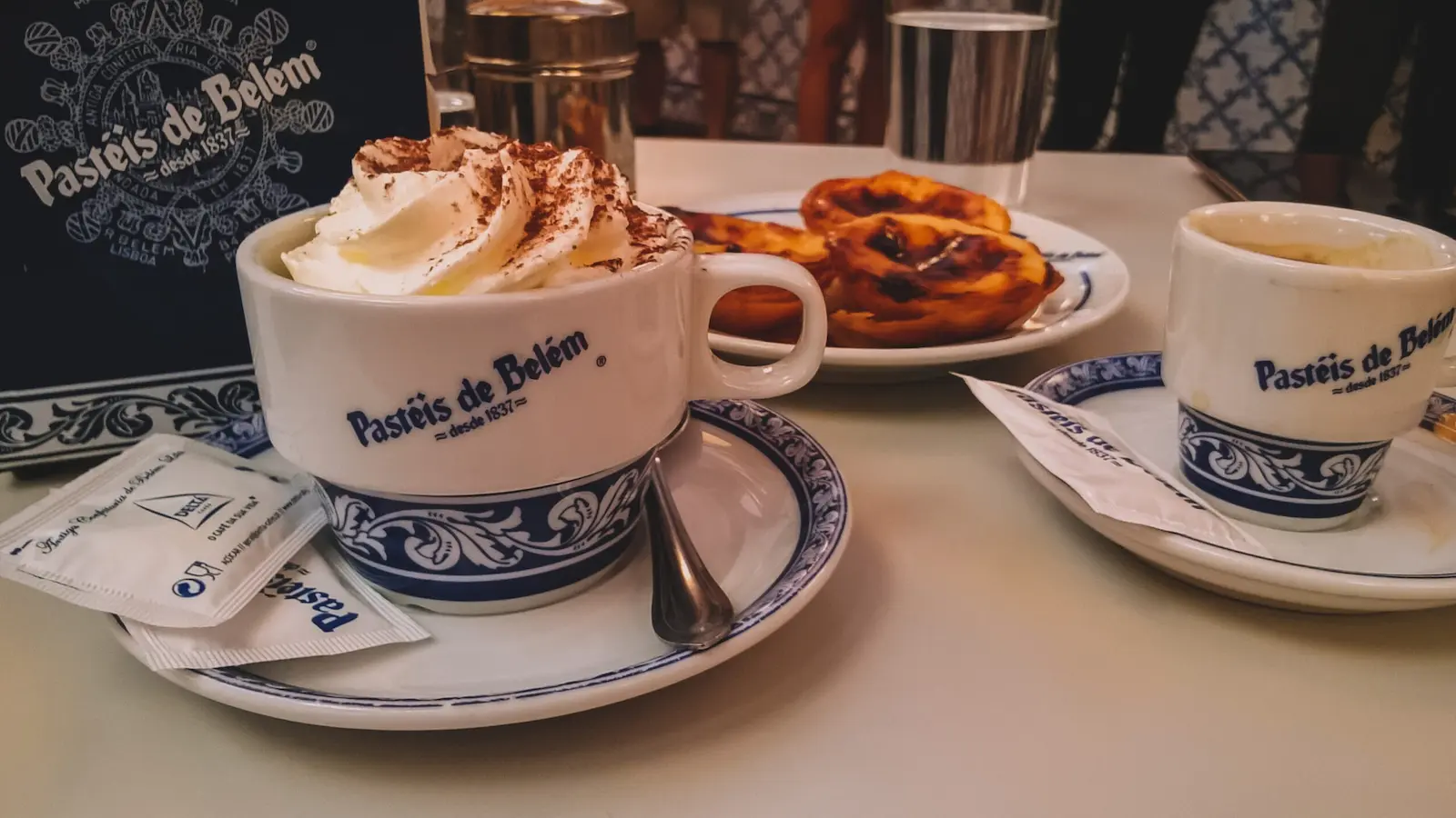 mangiare tra i quartieri di Lisbona foto di due tazzone di cappuccino e pasteis de nata