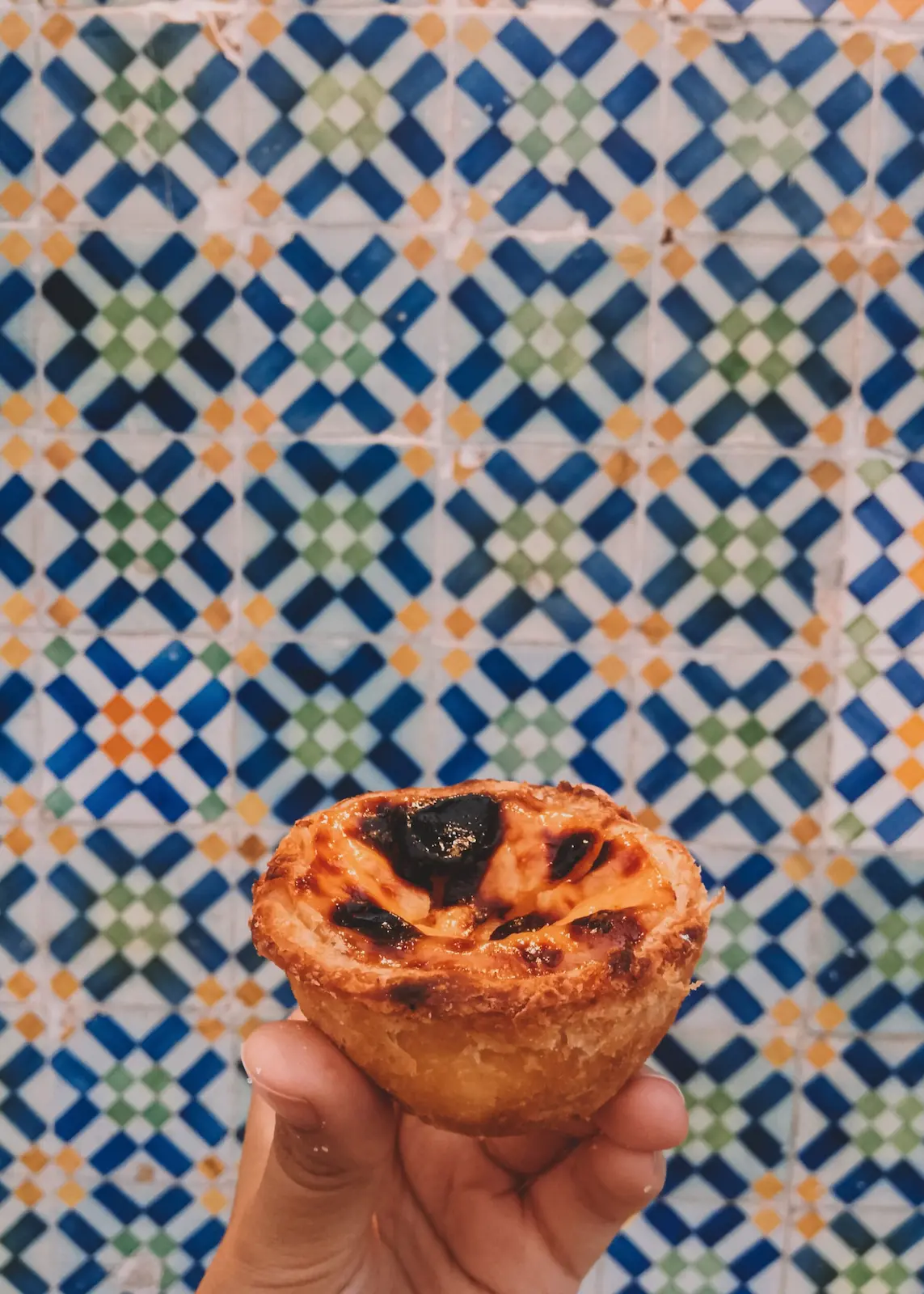 Pasteis de nata su sfondo di mattonelle al muro geometriche e colorate